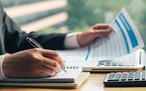 close up shot business man hands with pen writing notes paper other hand holding marketing chart min